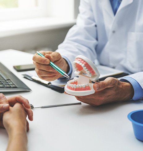 a dentist showing a patient a tooth model