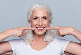 senior woman pointing to her smile 