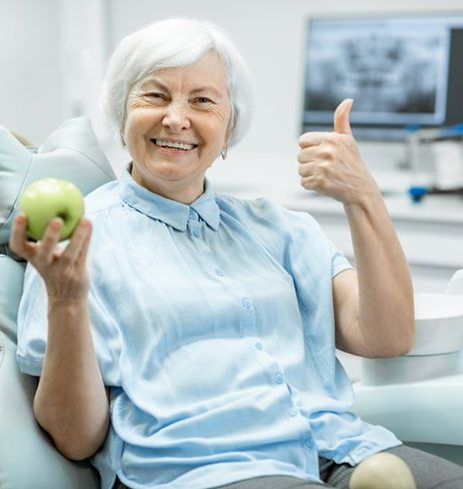 Woman giving thumbs-up for implant dentures in Dumfries