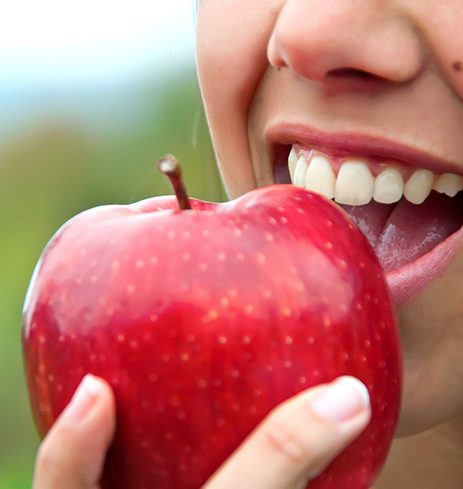 Closeup of patient with implant dentures in Dumfries eating an apple 
