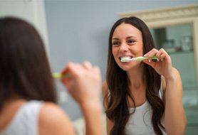 Woman brushing her teeth after dental implants in Dumfries, VA