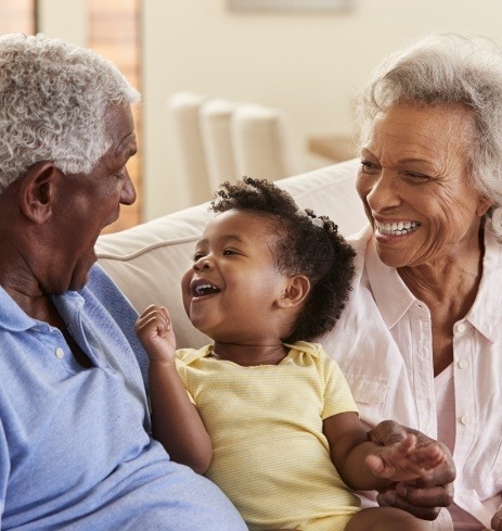 Older couple with grandchild enjoying the benefits of dental implants