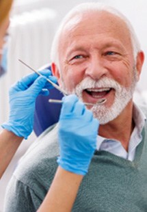 Mature man in grey sweater smiling at oral surgeon