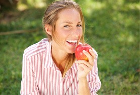 Woman with dental implants in Dumfries, VA about to eat an apple
