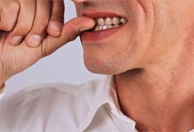 Man with dental implants in Dumfries, VA biting fingernails