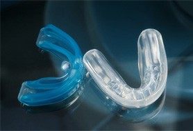 Two athletic mouthguards on a reflective table
