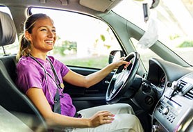 Woman in purple shirt smiling while driving home