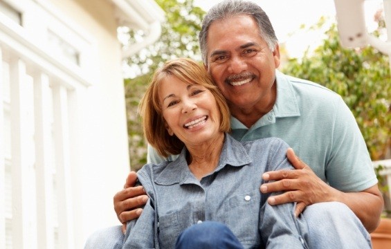 Man and woman smiling after tooth replacement with dental implants