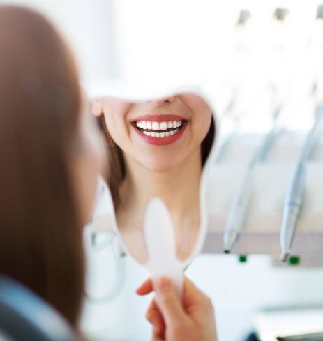 Woman looking at smile after facial cosmetic surgery