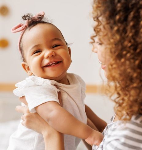 Baby smiles in mother’s arms