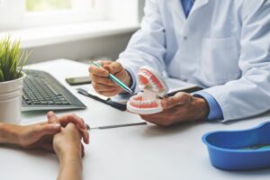 Doctor pointing to dental implant model.